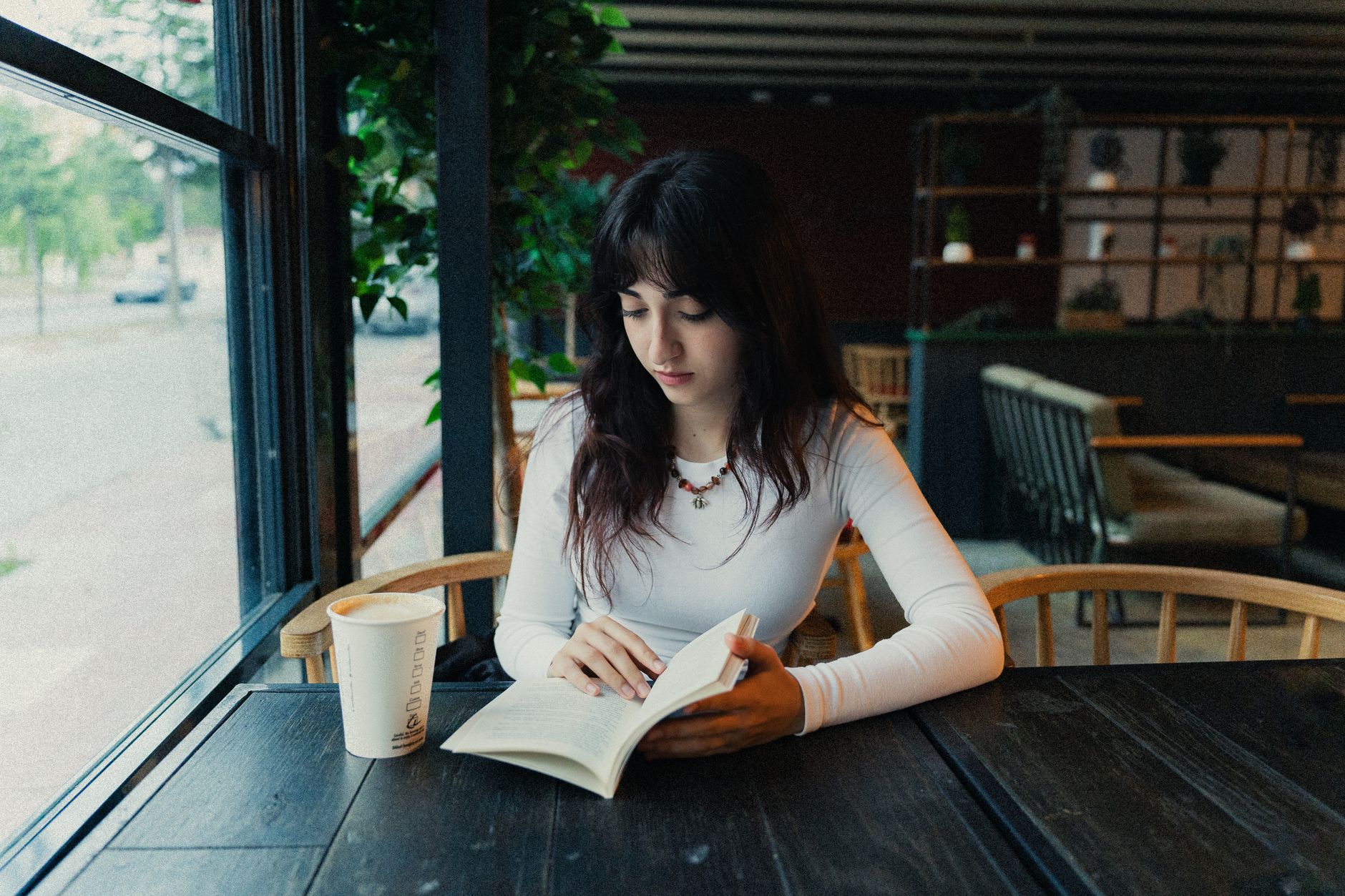 カフェの窓辺で本を読む女性