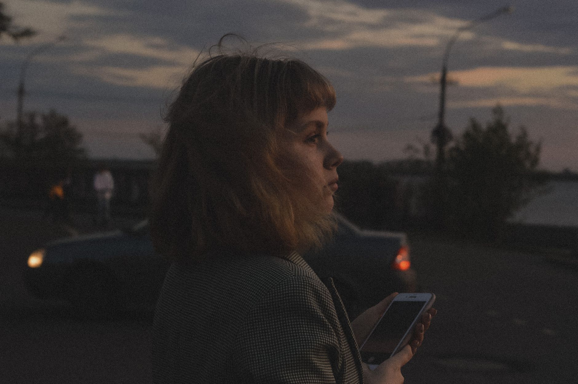 夕暮れにスマホを見て考える女性の横顔