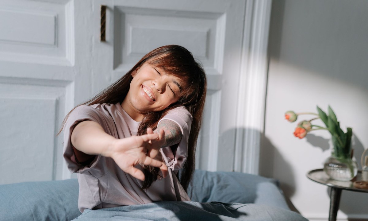 朝の光が差し込むベッドで目覚める女性