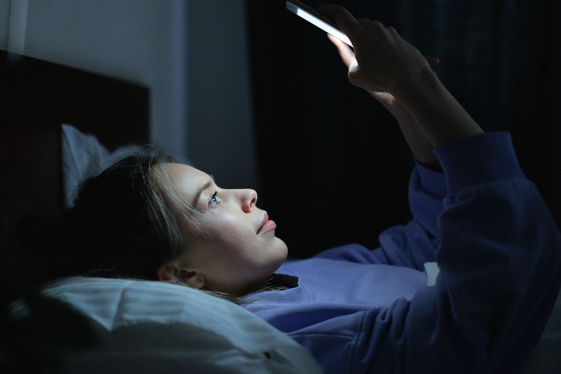 夜にスマホを見て考える女性