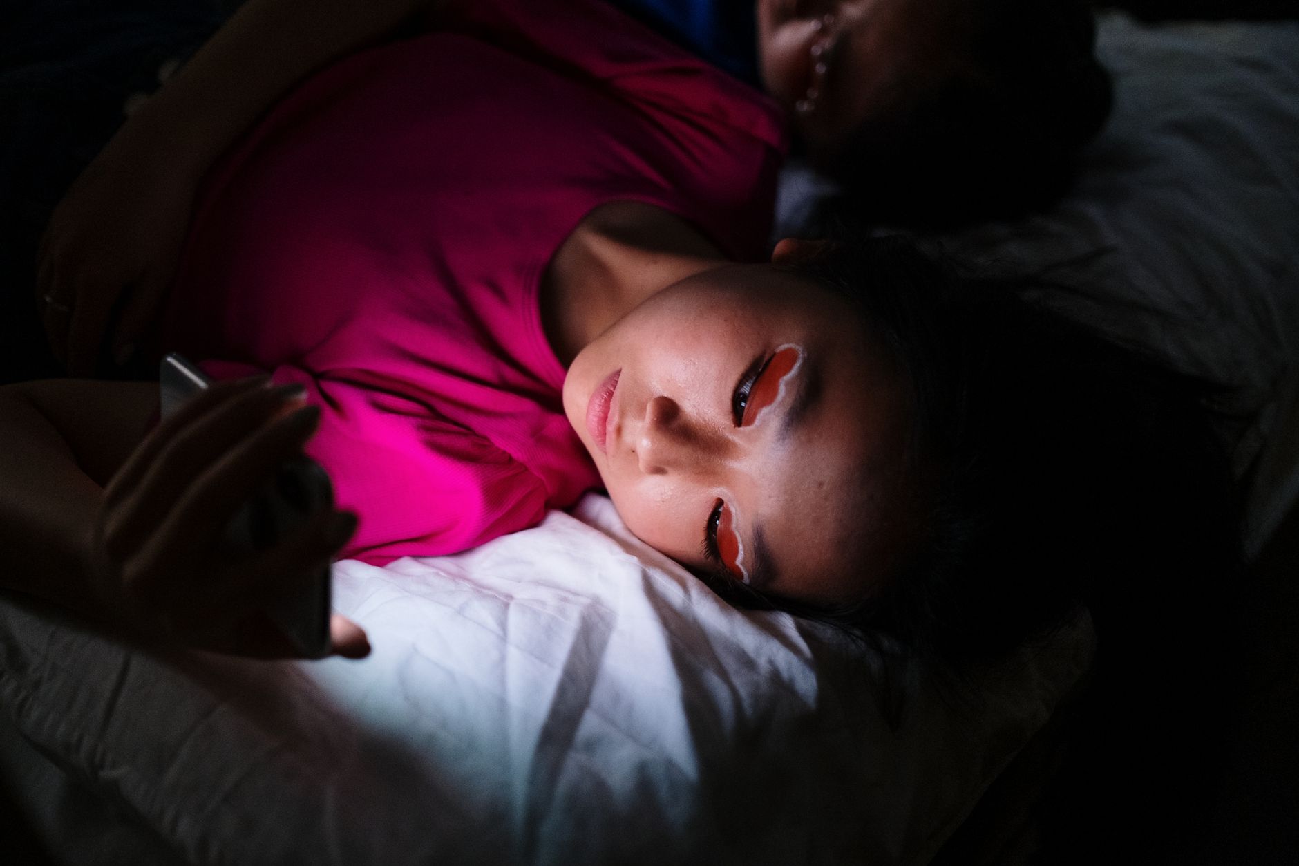 深夜、ベッドでスマホの時計表示11:11を見つめる女性